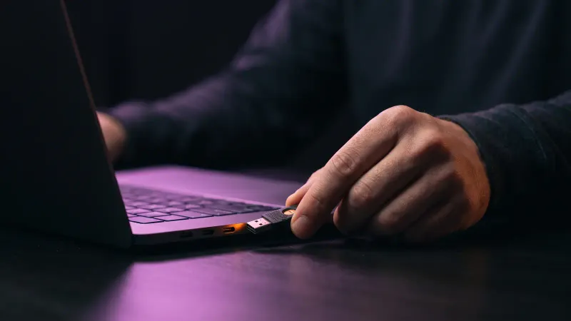 Hand holding a hardware security key near a laptop, showing careful handling of API keys and access for an integration