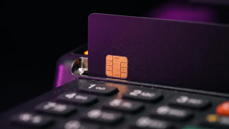 Macro of a payment card resting in a card reader chip slot, for the PCI DSS work an online store takes on