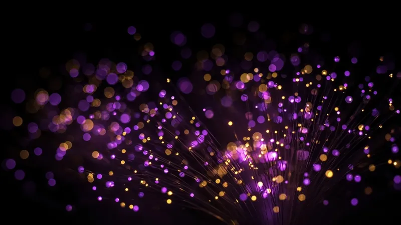 A close spray of fiber-optic strands glows violet and soft gold at the tips, with most points melting into bokeh on a black background.