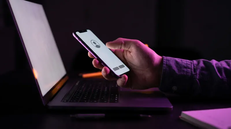 Phone sign in approval prompt held over a laptop, multifactor authentication at a Worcester accounting firm